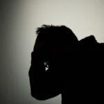 頭をかくシルエット像