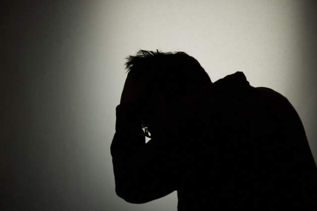 頭をかくシルエット像