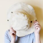 夏用帽子で顔を隠す